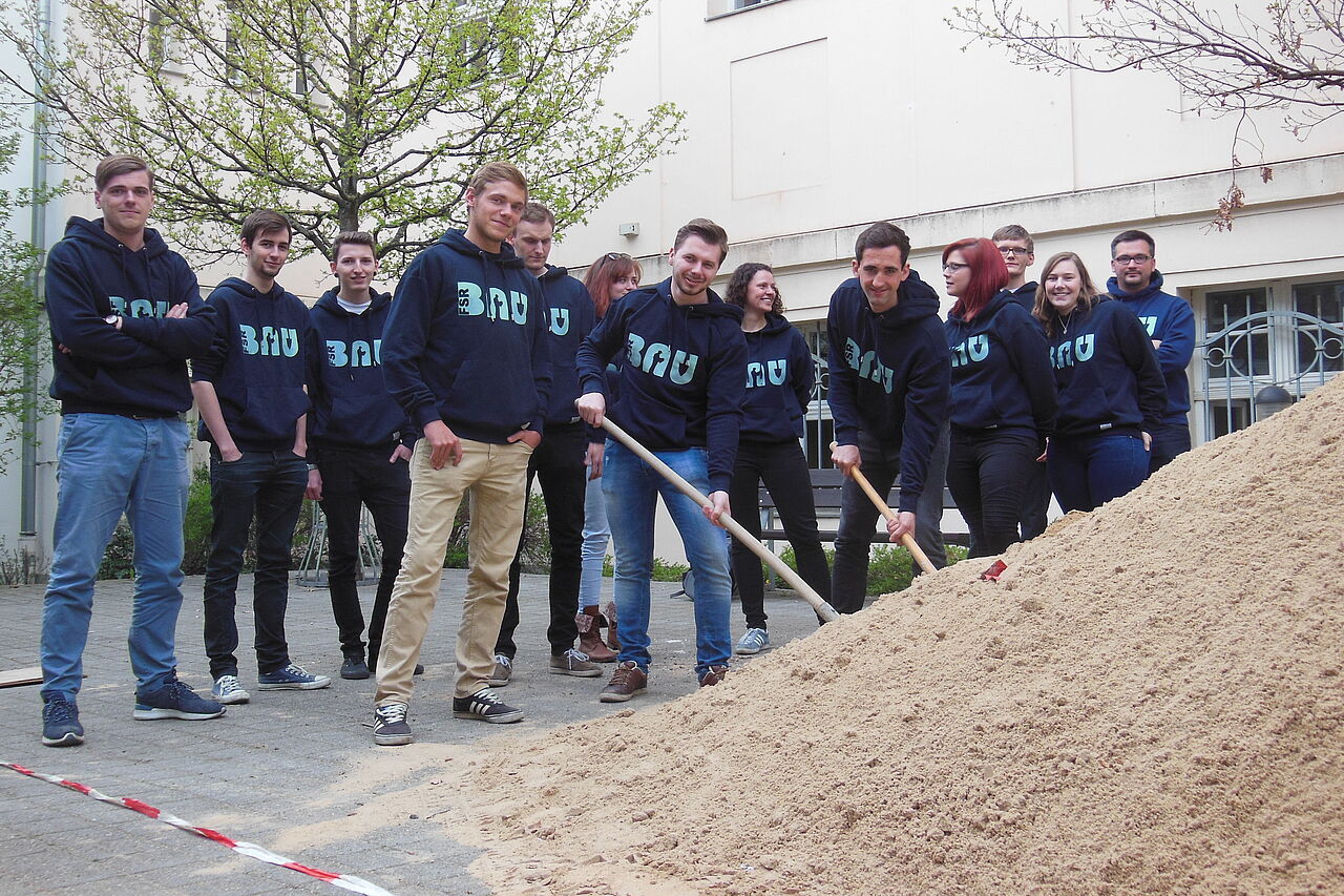 A student committee as team are about to shovel away a pile of sand